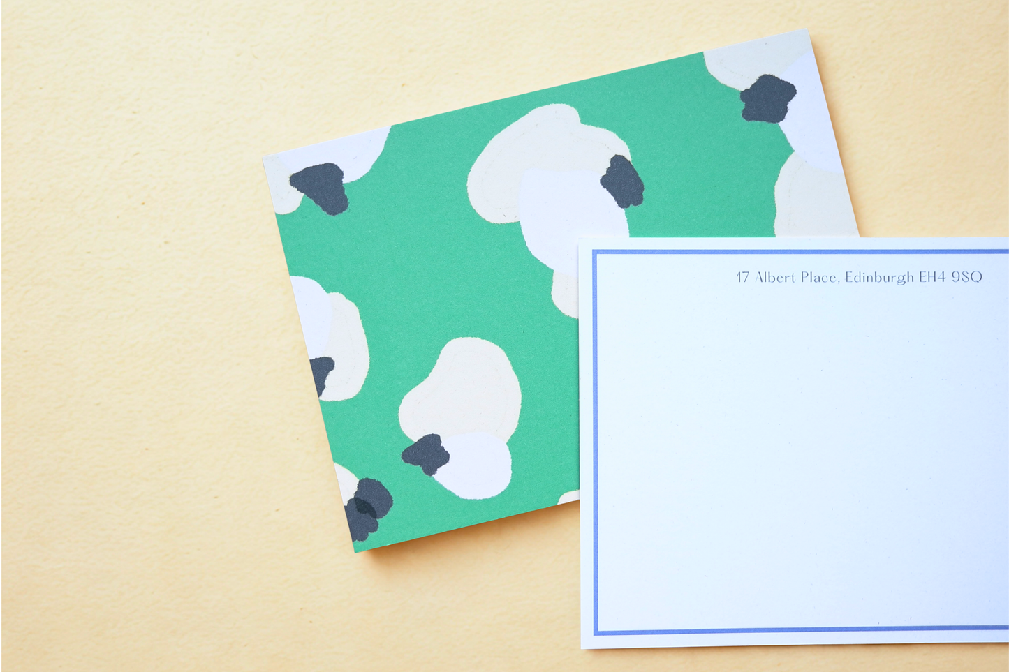 Notebook with abstract leopard print pattern on green cover and white pages on beige background.