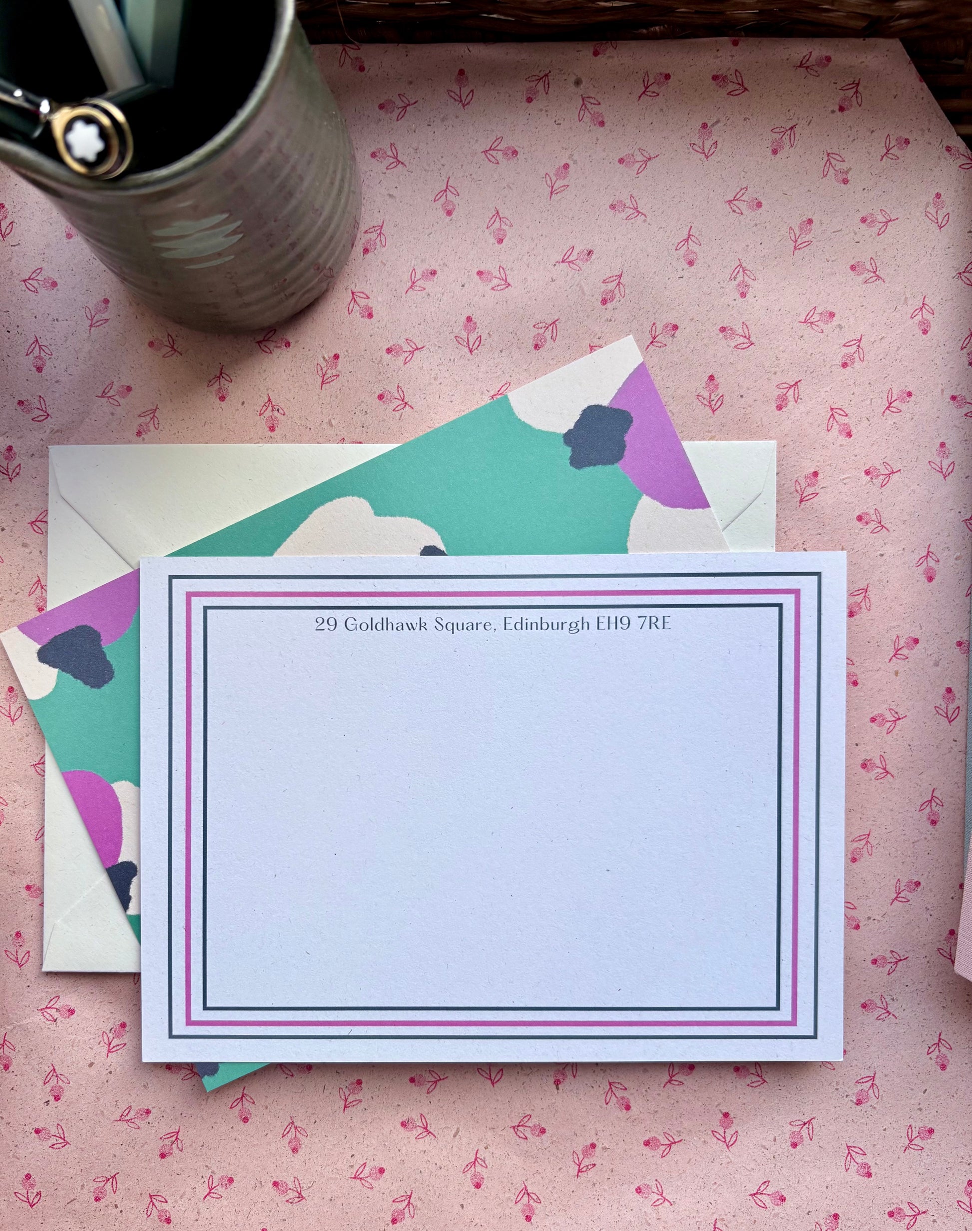 Stationery set with a card and envelope on a pink floral-patterned surface