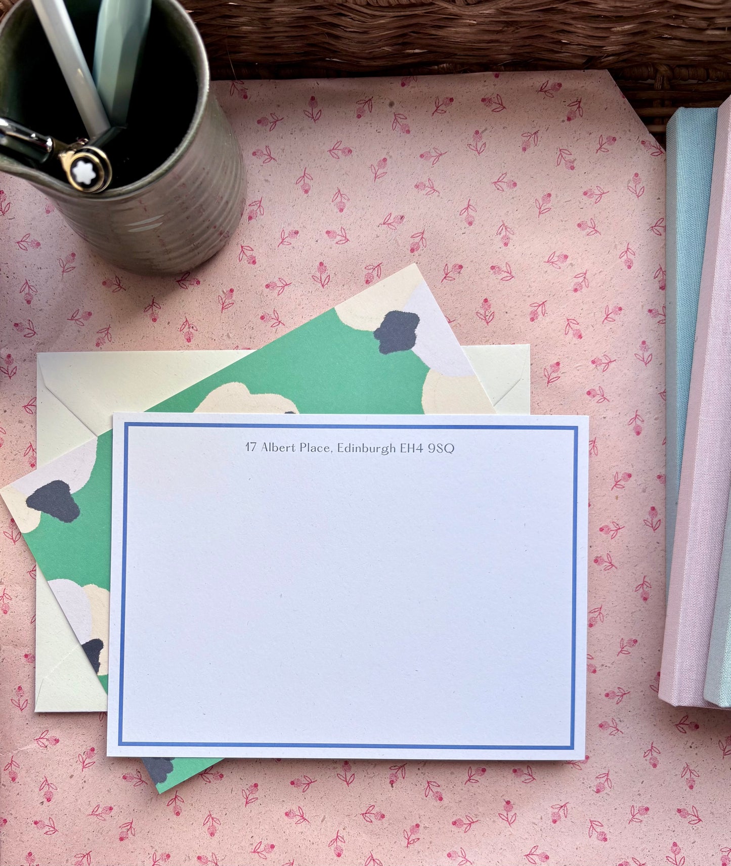 Stationery set with a correspondence card and envelope on a floral-patterned surface.