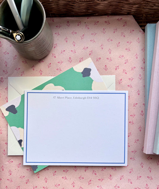 Stationery set with a correspondence card and envelope on a floral-patterned surface.